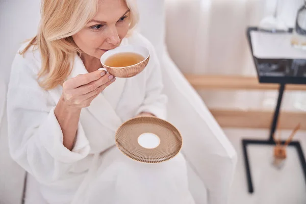 Mujer pensativa tomando un sorbo de té de manzanilla — Foto de Stock