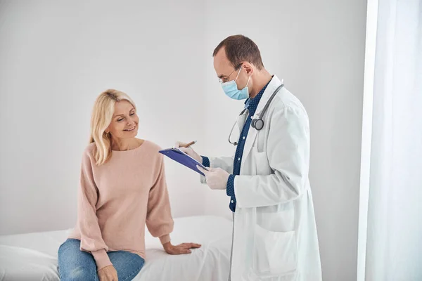 Médico concentrado toma notas de su salud de paciente femenino —  Fotos de Stock