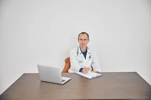 Medico in occhiali seduto sulla sedia nel suo ufficio — Foto Stock