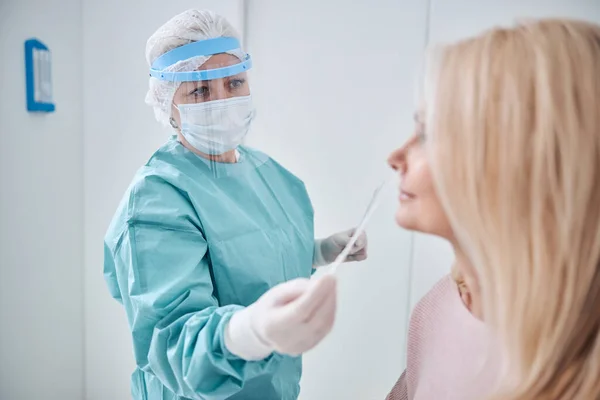 Infermiera professionista che esamina una donna per COVID-19 — Foto Stock