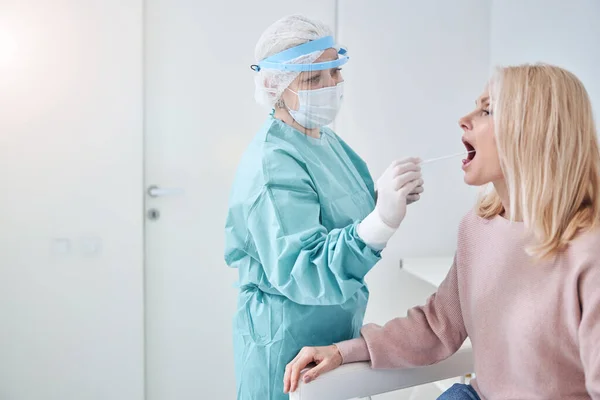 Qualified lab technician swabbing the patient throat — Stock Photo, Image