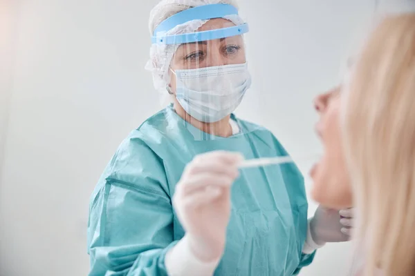 Virologist in sterile gloves swabbing the patient — Stock Photo, Image