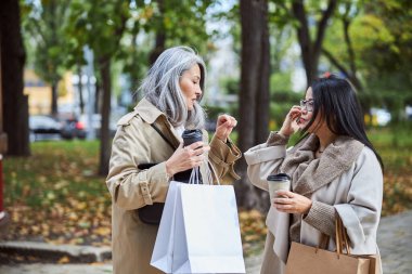Kahve içip sokakta sohbet eden iki zarif kadın.