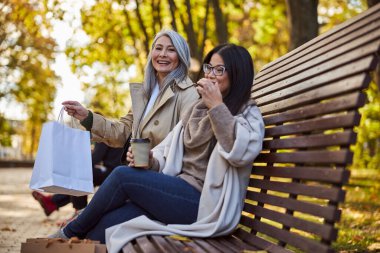 Parkta bankta oturan neşeli bayan arkadaşlar