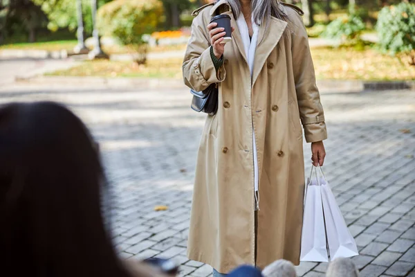 Elegant kvinde med kop kaffe stående på gaden - Stock-foto