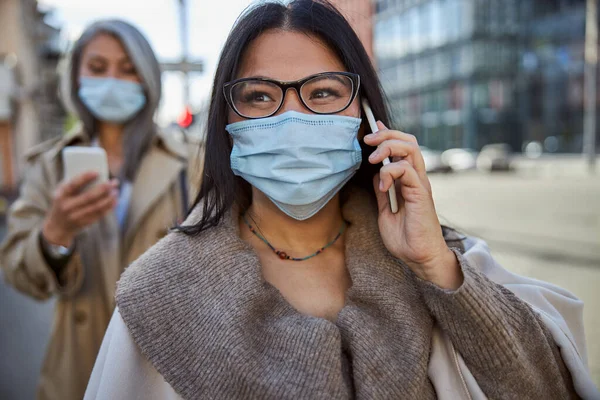 Charmante Frau in medizinischer Maske telefoniert im Freien — Stockfoto