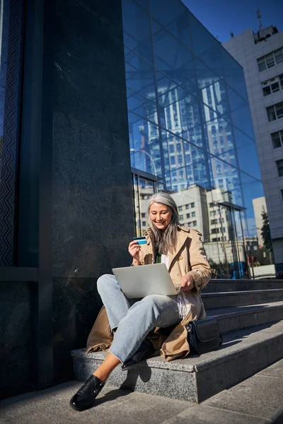 Радостная женщина с кредитной картой с помощью ноутбуков для онлайн-покупок — стоковое фото