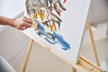 Beyaz tenli ressam tripod sehpasında çalışıyor.