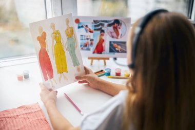 Elinde çizimler tutan kulaklıklı bir kız.