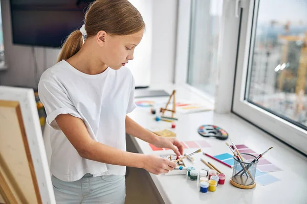 Serious joven pintor elegir los colores adecuados para su pintura — Foto de Stock