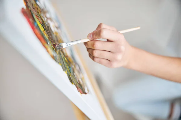 Młody artysta ręcznie maluje obraz w pracowni — Zdjęcie stockowe