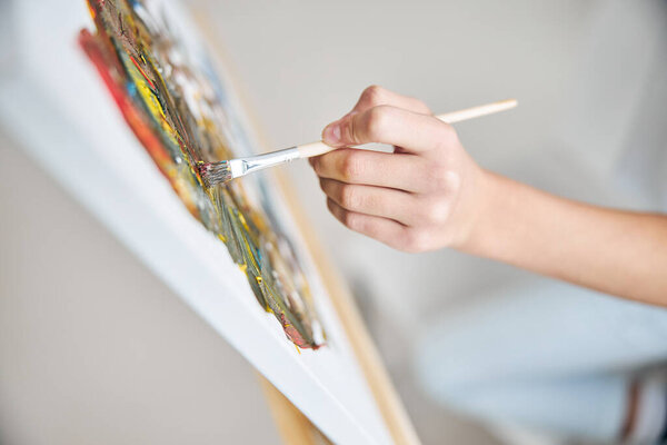 Young artist hand painting a picture in the home studio