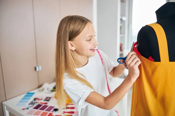 Costurera sonriente cortar una tira de tela con tijeras — Foto de Stock