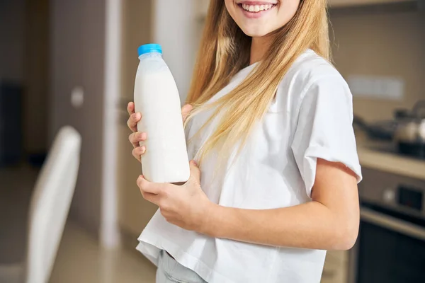 Junge Dame mit Milchprodukt steht in der Küche — Stockfoto