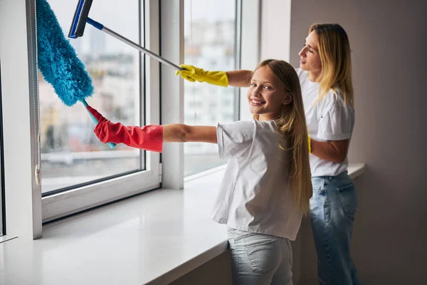 Woman and her daughter washing the windowpane — Stock Photo, Image