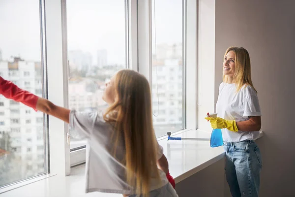 Mädchen hilft ihrer Mutter beim Fensterwaschen — Stockfoto