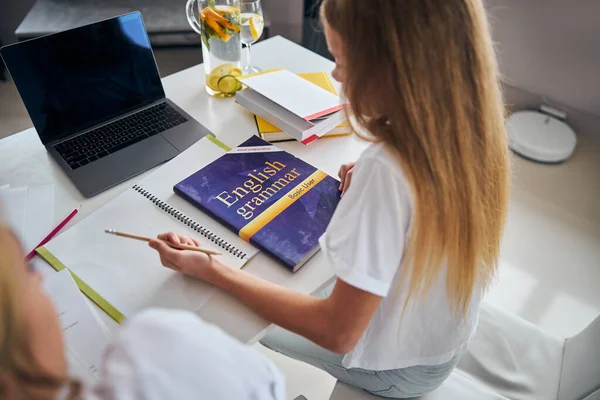 Dotter sitter med sin anteckningsbok över hemuppgiften — Stockfoto