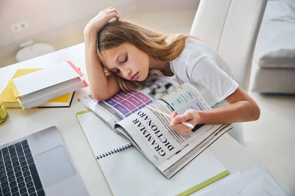 Сонний підліток кладе голову вниз, читаючи правила граматики — стокове фото