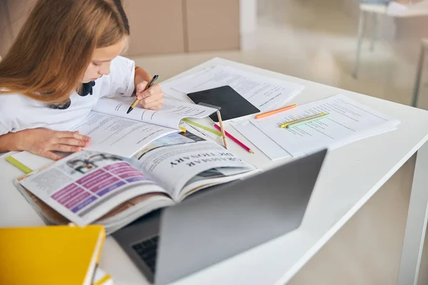 Étudiante concentrée traçant ses progrès de lecture avec un éco-stylo — Photo