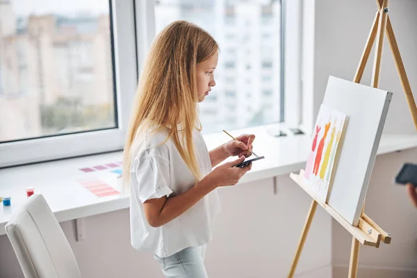 Alumnos pintando mujeres en vestidos en una hoja de papel — Foto de Stock