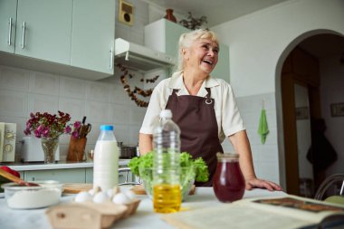 Mutfakta yemek pişiren neşeli son sınıf kadını.