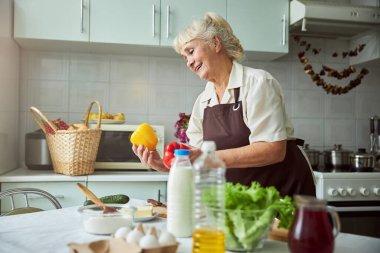 Büyüleyici yaşlı kadın mutfakta yemek pişiriyor.