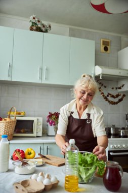 Güzel yaşlı bayan mutfakta yemek pişiriyor.