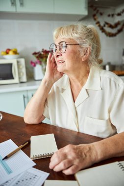 Evdeki masada oturan mutsuz yaşlı kadın.