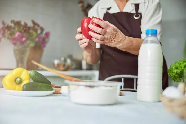 Yaşlı bir kadın mutfakta yemek pişiriyor. — Stok fotoğraf