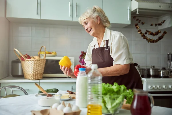 Büyüleyici yaşlı kadın mutfakta yemek pişiriyor.