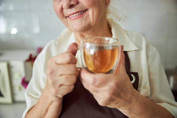 Радостная старуха со стеклянной чашкой чая — стоковое фото