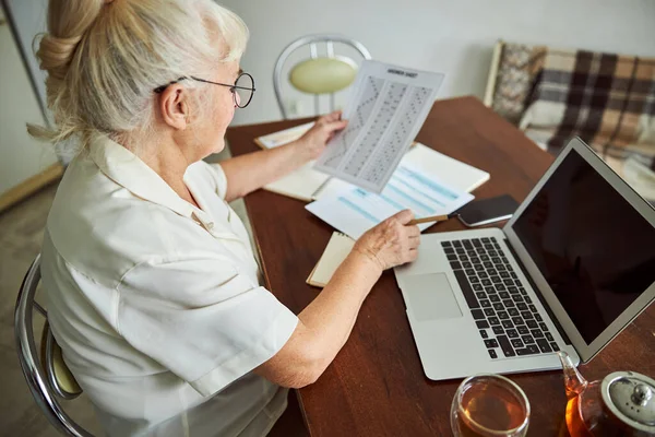 Seniorin benutzt Notebook und macht Test zu Hause — Stockfoto