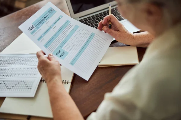 Mujer mayor llenando formulario de impuestos en casa — Foto de Stock