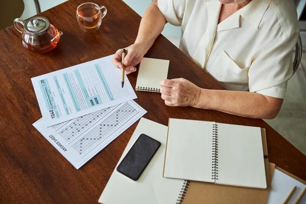 家で納税申告書を記入する高齢女性 — ストック写真
