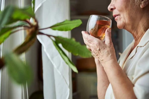Пожилая женщина пьет травяной чай дома — стоковое фото