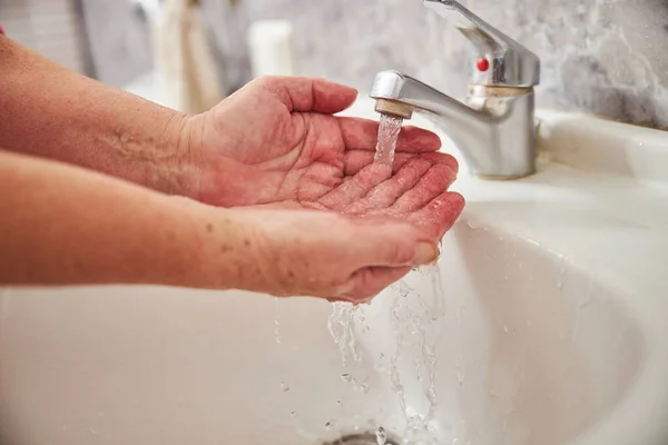 Seniorin wäscht sich unter fließendem Wasser die Hände — Stockfoto