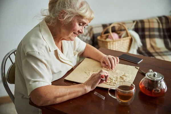 Niza mujer mayor haciendo imagen de arcilla polimérica en casa —  Fotos de Stock