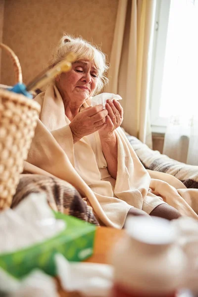 Mulher velha infeliz com gripe usando lenço — Fotografia de Stock