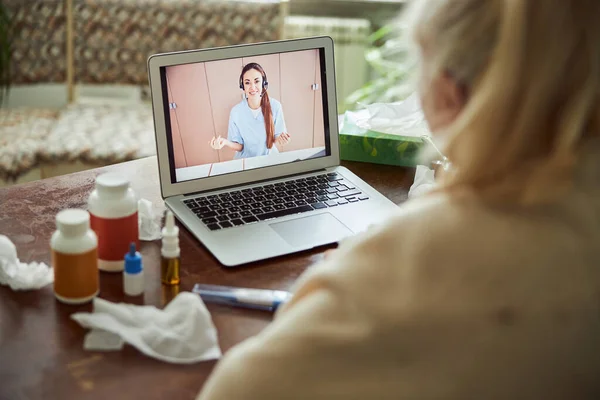 Old lady with flu having online consultation with doctor at home