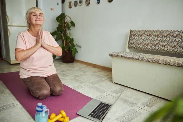 Güzel yaşlı kadın evde yoga yapıyor.