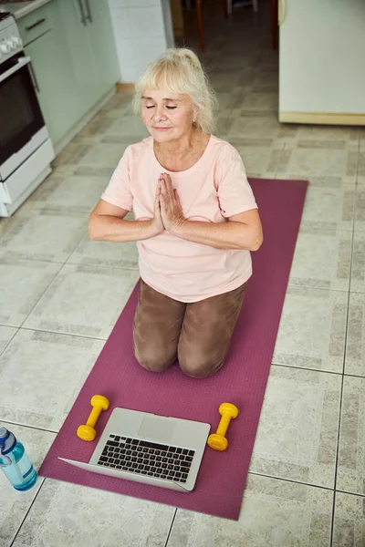 Huzurlu yaşlı kadın evde meditasyon yapıyor.