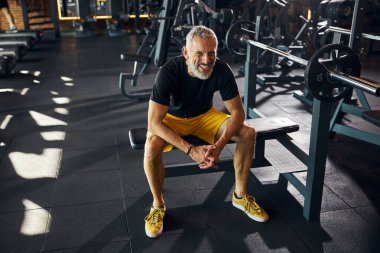 Kameraya poz veren neşeli, olgun bir sporcu.