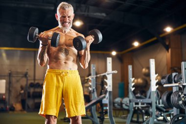 Sporcu ağırlıkları göğsüne doğru kıvırıyor.