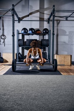 Odaklanmış Afrikalı Amerikalı vücut geliştirici kaldırma işini yapıyor.