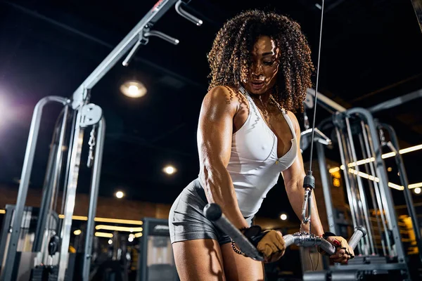 Muskularna kobieta korzystająca z urządzenia fitness podczas treningu siłowego — Zdjęcie stockowe