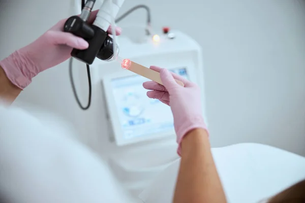 Arzt in Latex-Handschuhen testet ein Schönheitsgerät — Stockfoto
