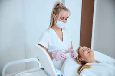 Odaklanmış dermatolog hastasını tedavi etmeye hazırlanıyor.