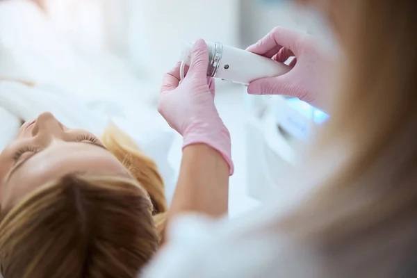 Vrouwelijke arts die de apparatuur voor de cosmetische ingreep aanpast — Stockfoto