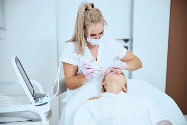Косметолог лечит пациента с помощью современного косметического оборудования — стоковое фото