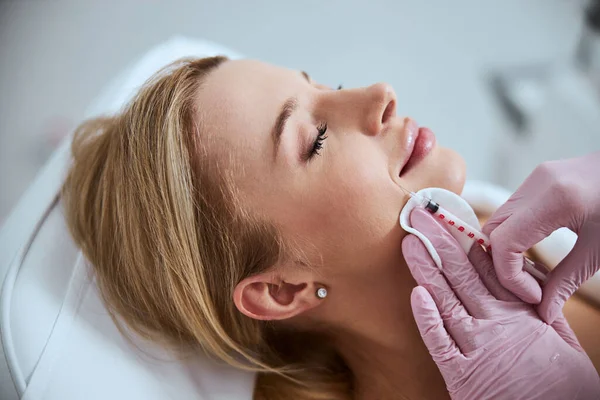 Cosmetólogo experimentado reduciendo los pliegues nasolabiales del paciente — Foto de Stock